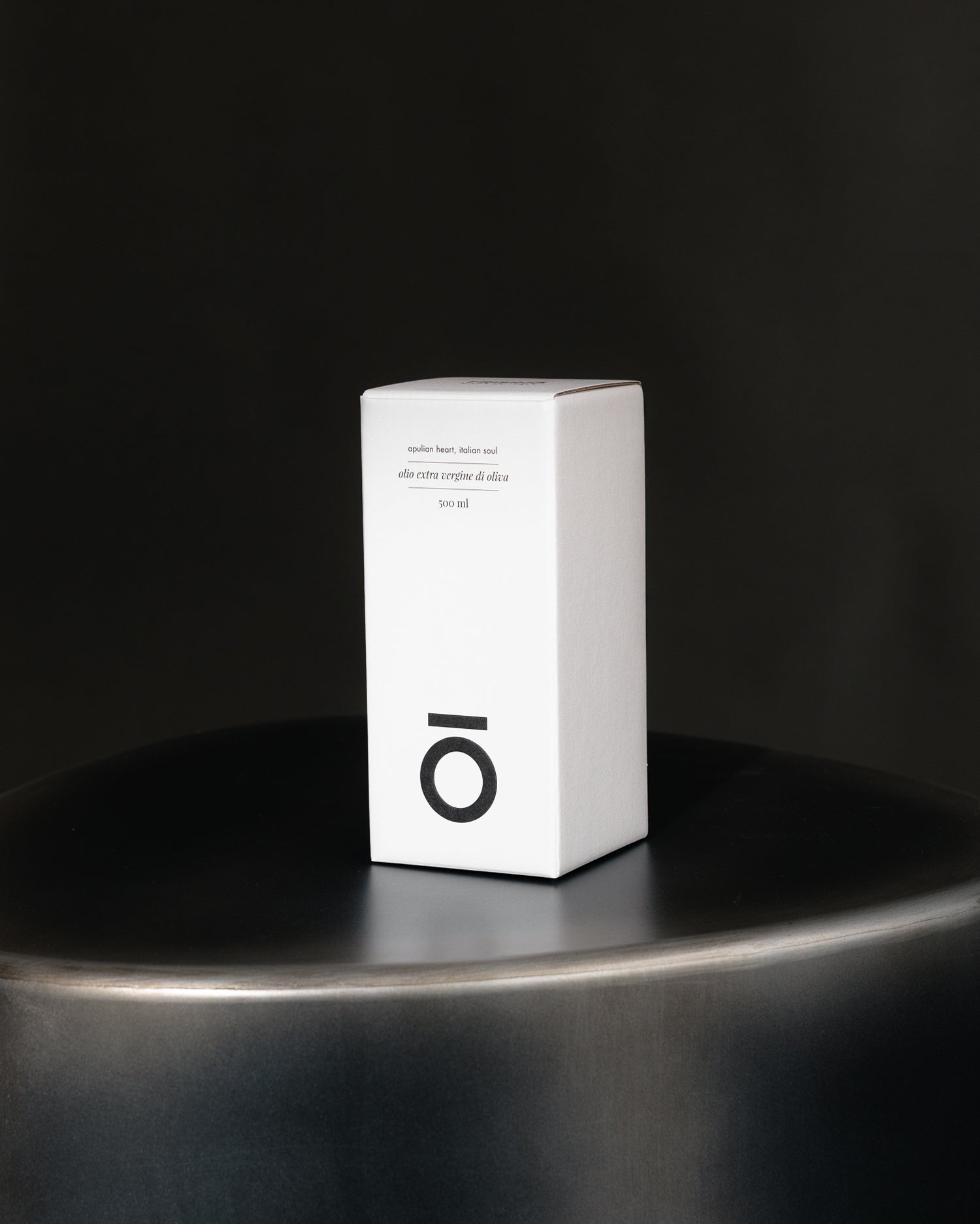 White Frisino gift box for extra virgin olive oil 500 ml on dark metal surface against black background