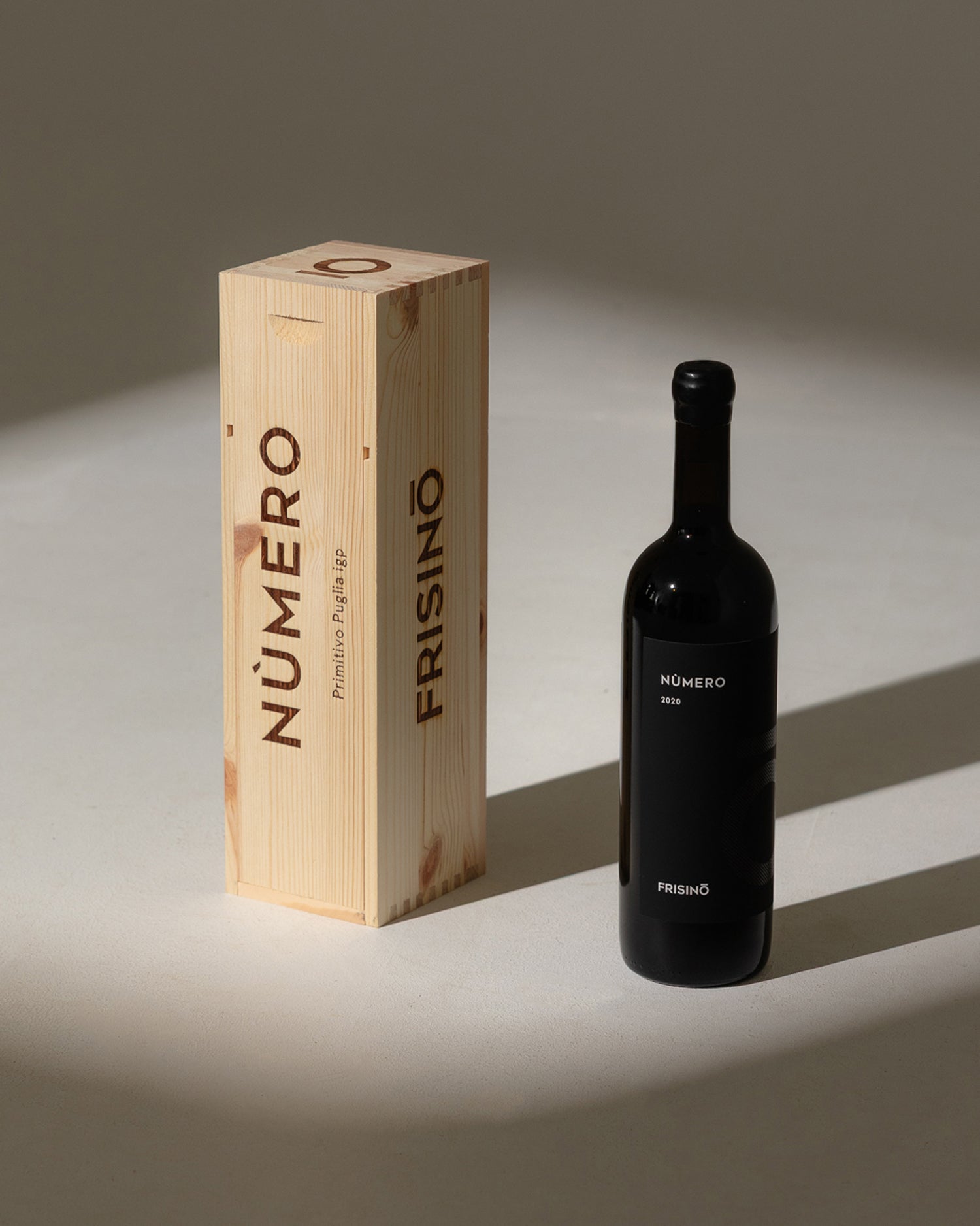 Frisino Nùmero wooden wine box beside the black 2020 Primitivo Puglia IGP bottle in natural light